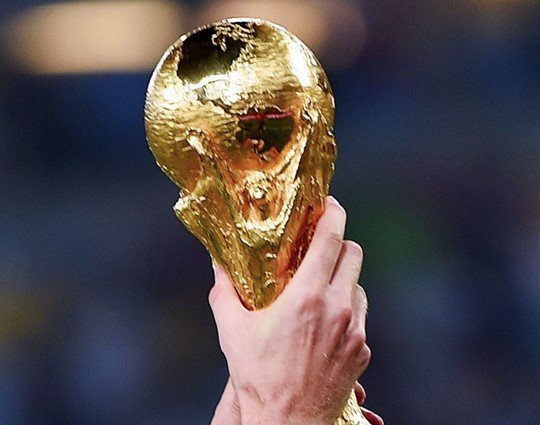 A hand holding up the FIFA World Cup Trophy.